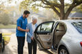 Caring driver helping an elderly person get into a sedan for medical transportation